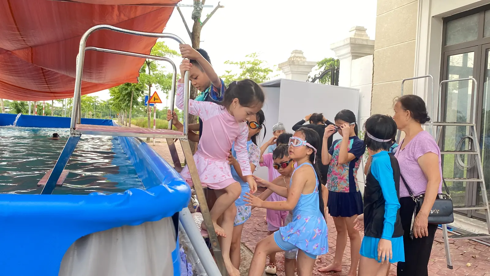 Các em xếp hàng và hỗ trợ nhau xuống hồ bơi an toàn