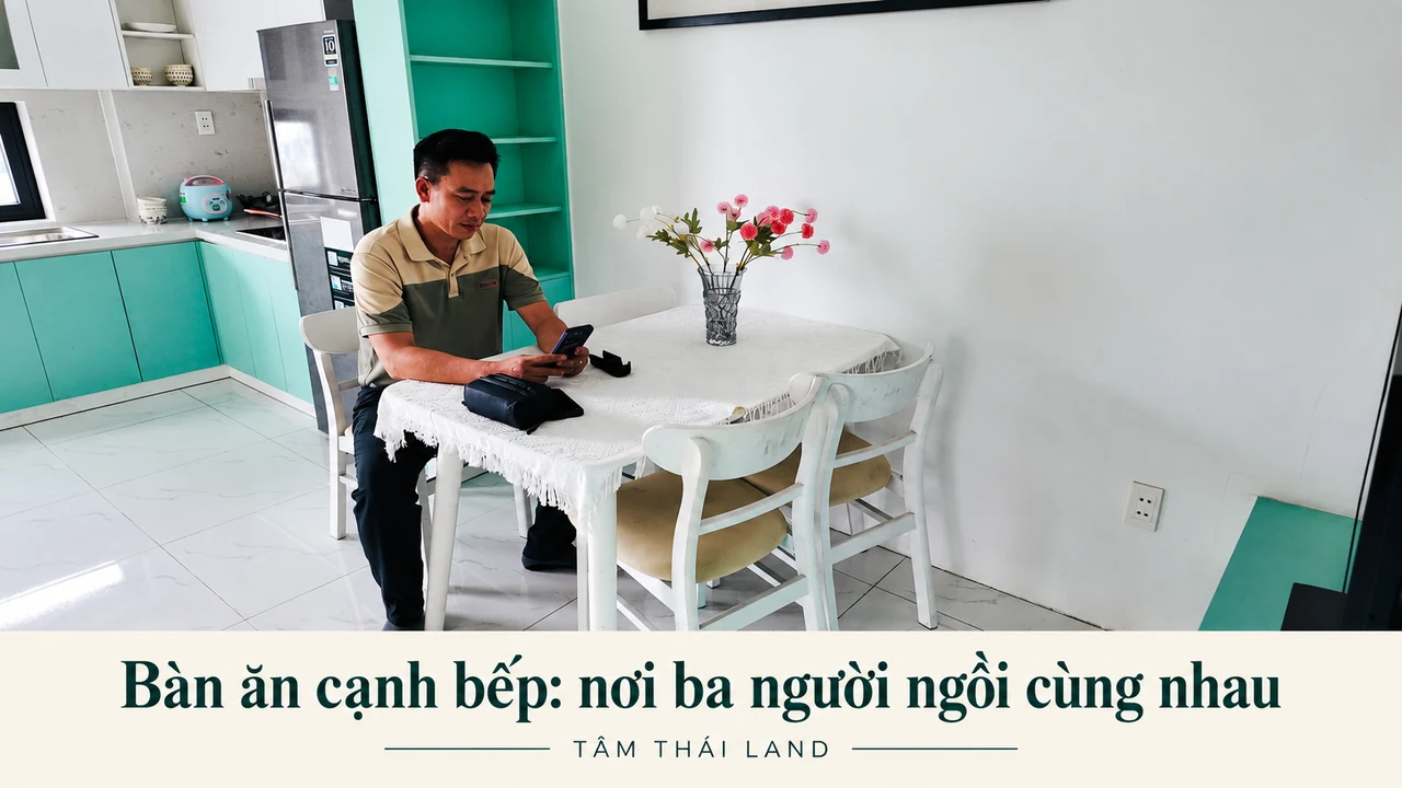Một người ngồi tại bàn ăn cạnh bếp màu xanh trong căn mẫu 2PN Nhà ở xã hội Thăng Long.