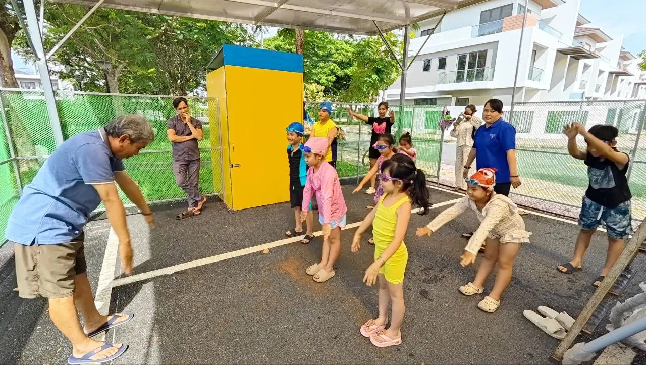Trẻ em khởi động trên cạn trước khi tham gia buổi học bơi cộng đồng