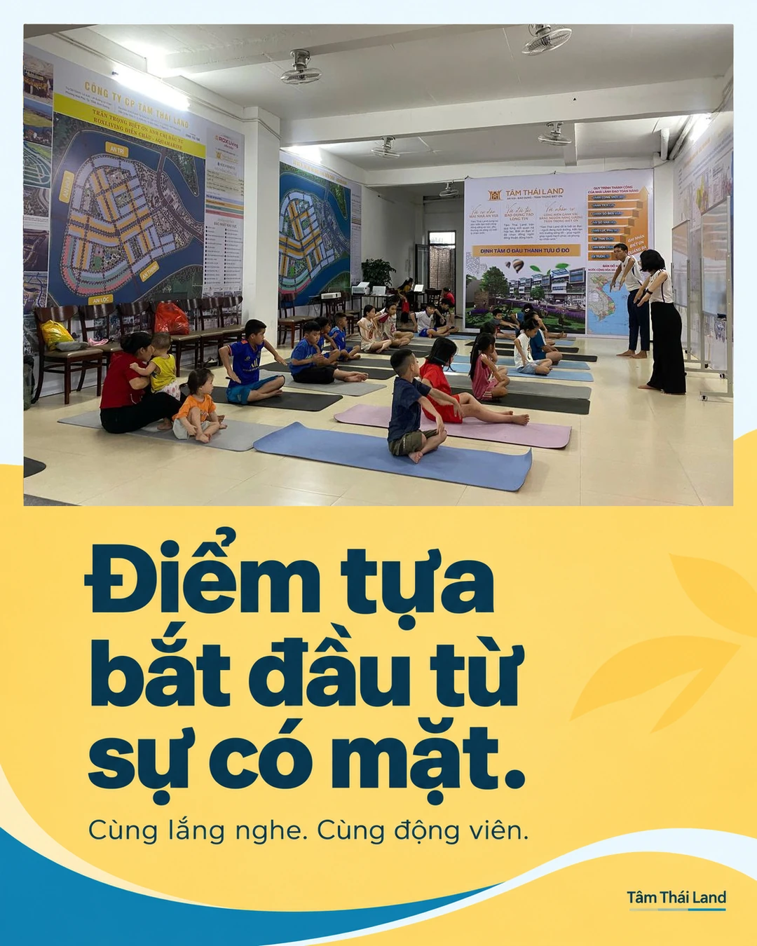 Người lớn và trẻ em ngồi trên thảm, bên trái có người bế em nhỏ; trên tường là bảng ROX Living Diễn Châu và Tâm Thái Land.