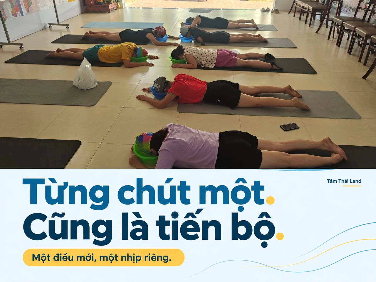 Nhóm người lớn nằm trên thảm, đội mũ bơi và tập với chậu nước trong không gian sinh hoạt tại Aquamarine.