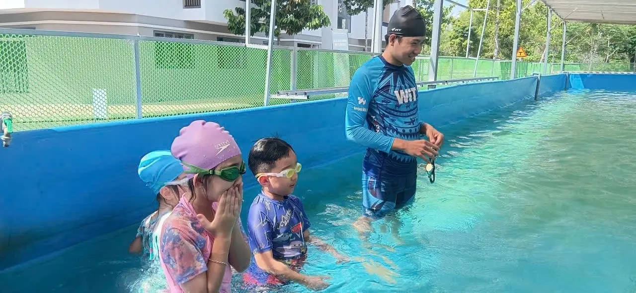 Trẻ em học cách đứng yên và giữ nhịp thở trong hồ bơi cùng người hướng dẫn