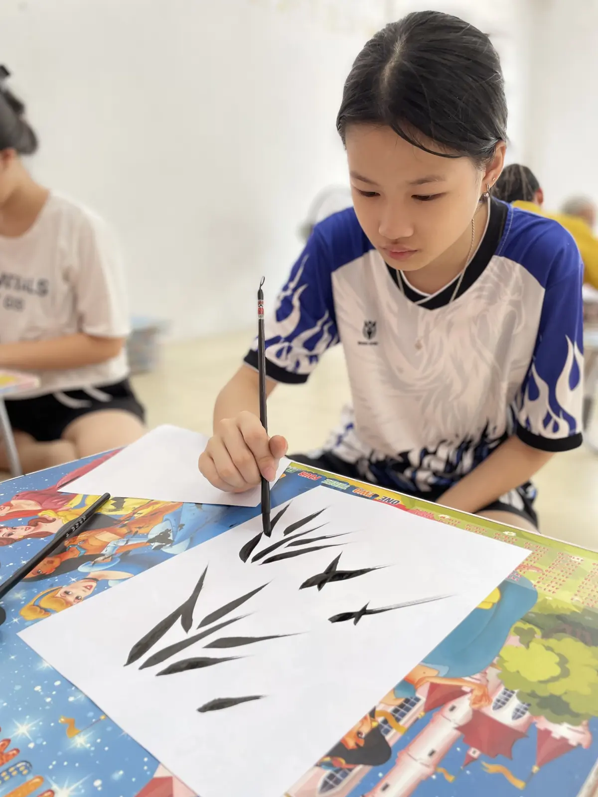 Các con tập trung luyện từng nét bằng bút lông trong chương trình thư pháp cộng đồng